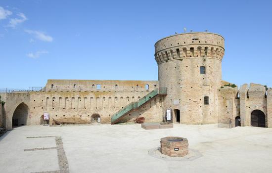 Imponente torre medievale in pietra, evoca storia e mistero sotto un cielo azzurro.
